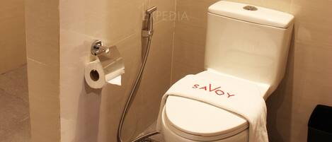 A bathroom with a toilet, a shower, and a towel rack with a towel.