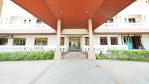 A covered walkway leading to a building with a traditional architectural style, featuring a tiled roof and multiple windows. - Amorn Sukhothai Hotel (Sukhothai)