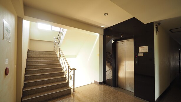 A staircase leading to an elevator in a building. - Amorn Sukhothai Hotel (Sukhothai)