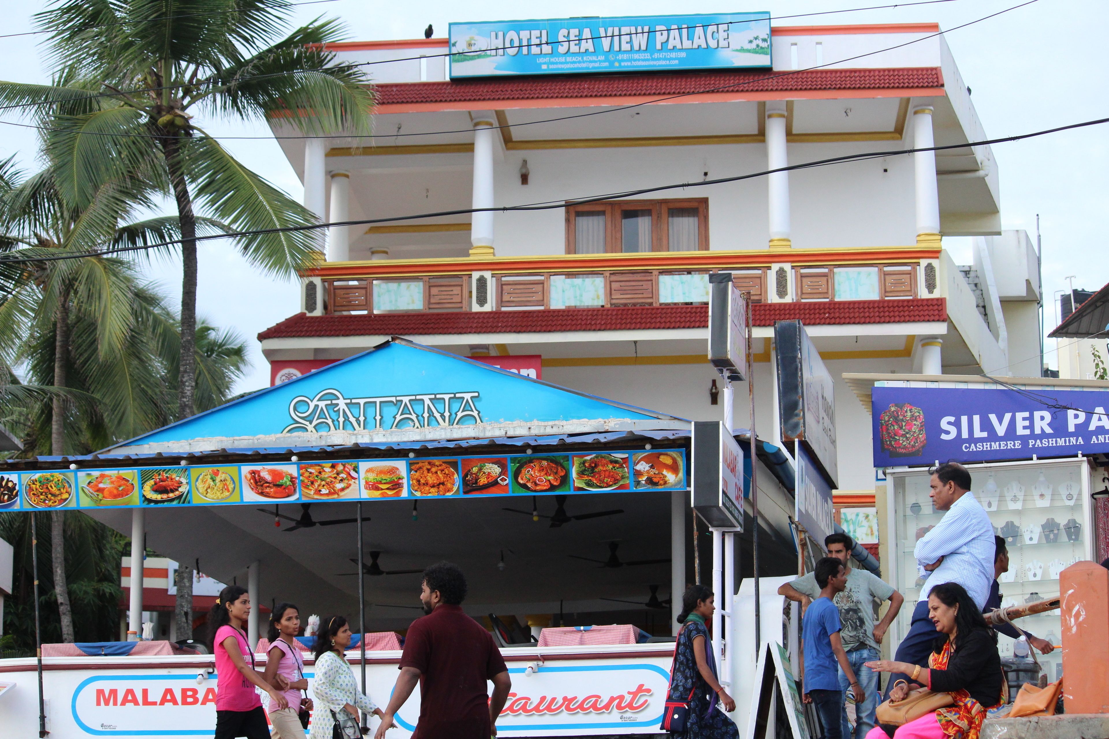 A restaurant with a blue awning and a signboard displaying various food items.
