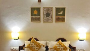 A hotel room with a bed, two wall-mounted lamps, and three wall art pieces depicting sun, moon, and stars.