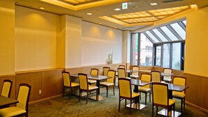 A conference room with multiple tables and chairs, large windows, and a skylight.