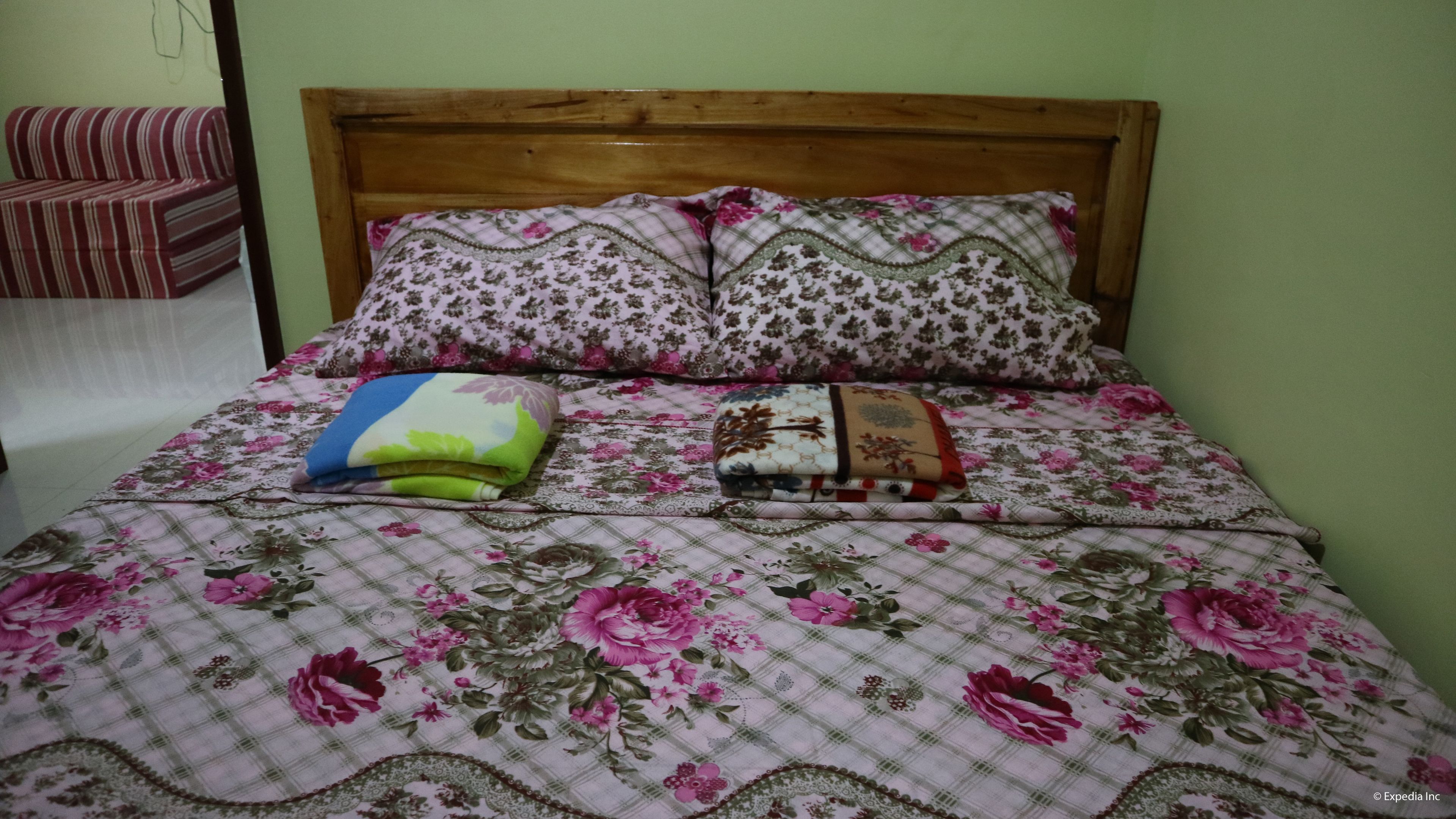 Una cama con ropa de cama floral, dos almohadas y una manta a rayas.