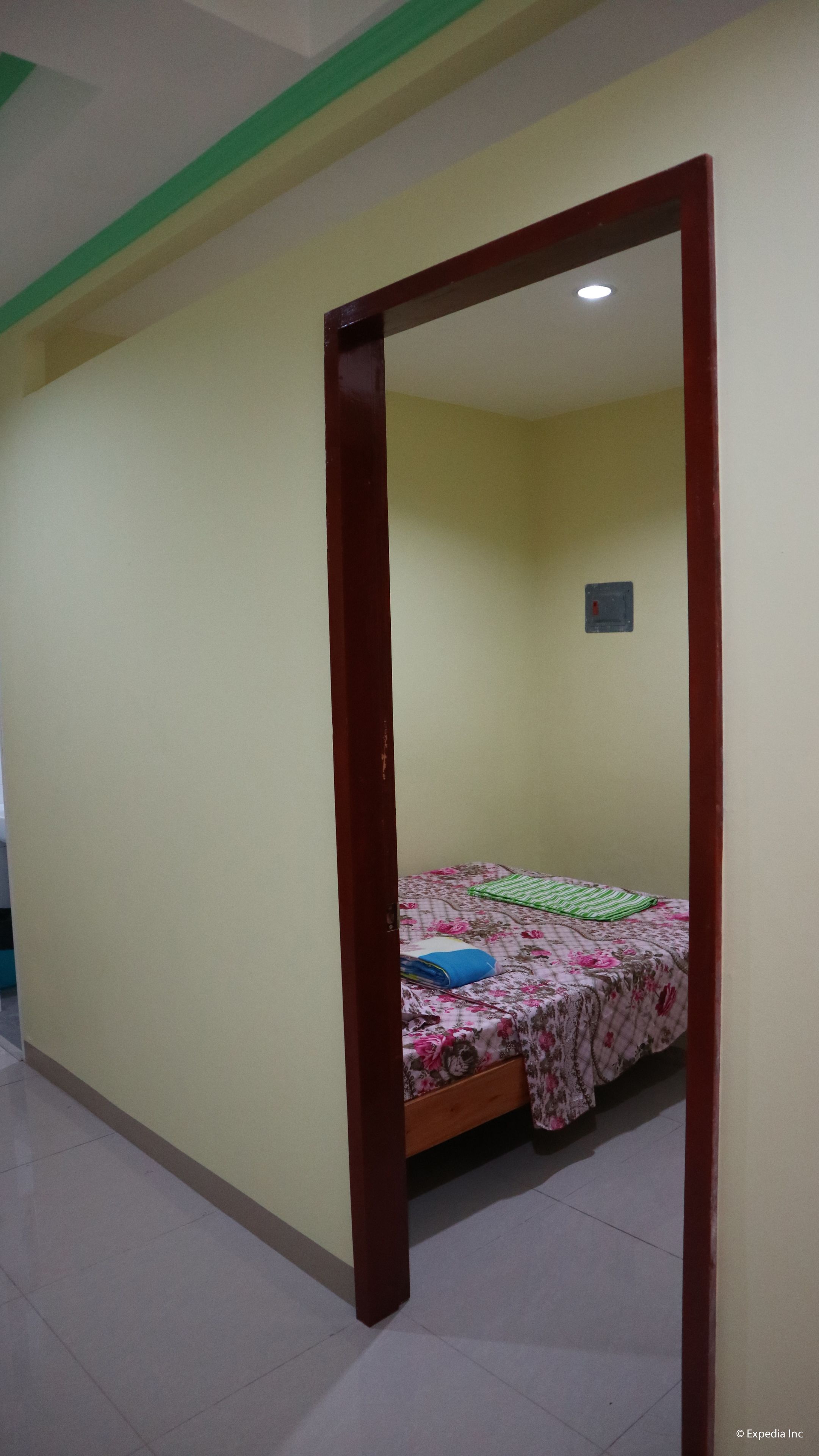 Ein Zimmer mit einem Bett, einem Holzrahmen für die Tür und einem kleinen Fenster.