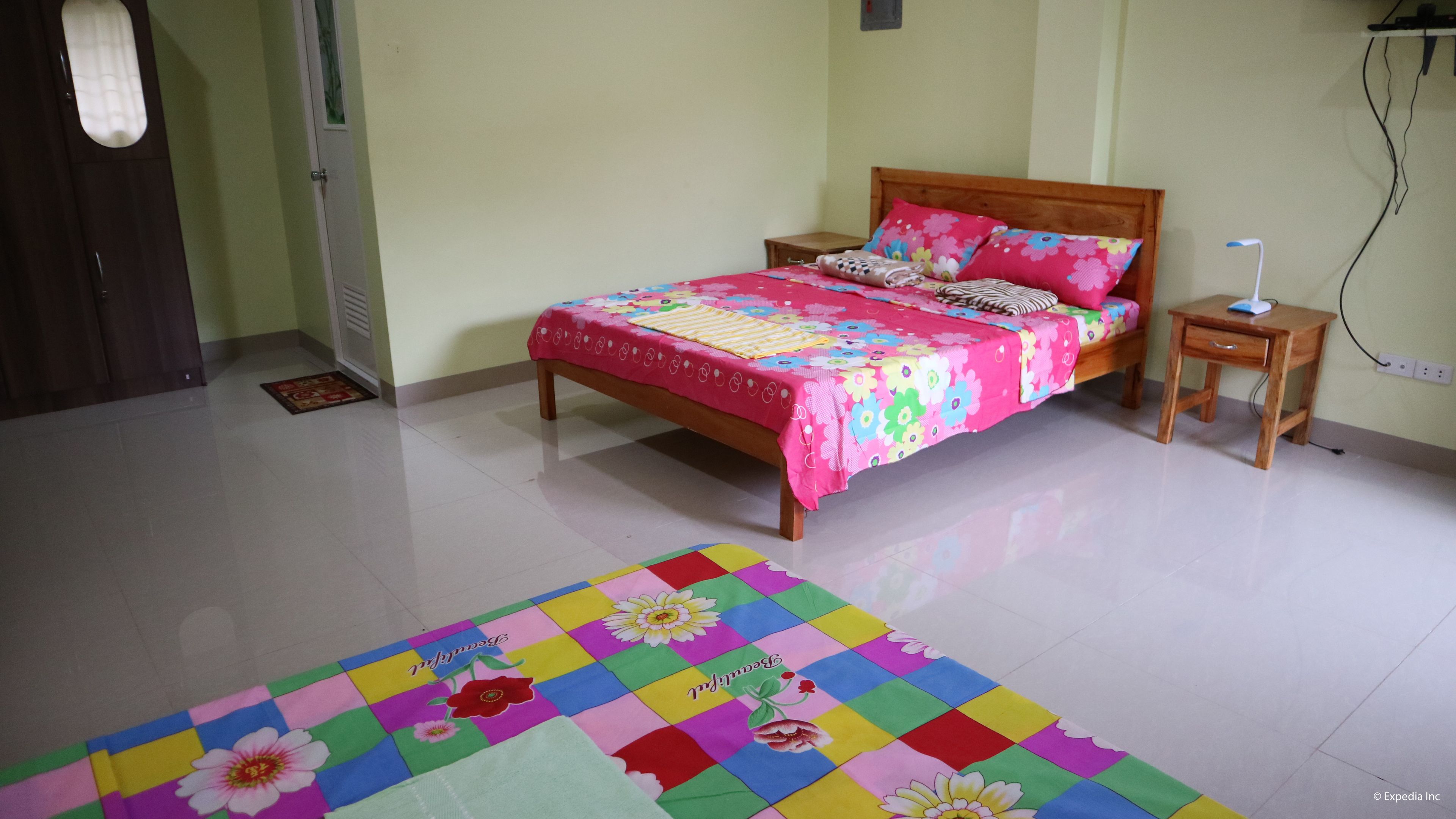 Quarto com cama, mesa de cabeceira e um tapete colorido.