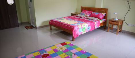 Quarto com cama, mesa de cabeceira e um tapete colorido.