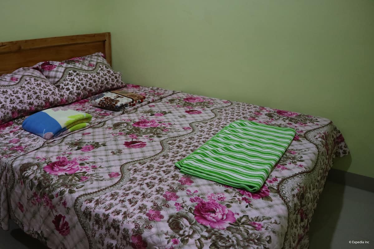 A bed with floral bedding, a wooden headboard, and a green striped blanket.