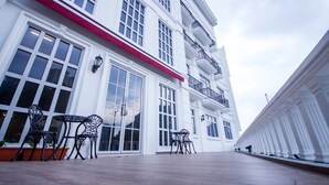 A multi-story building with large windows and a red awning. There are outdoor tables and chairs in front. - Wifi Boutique Hotel (George Town)