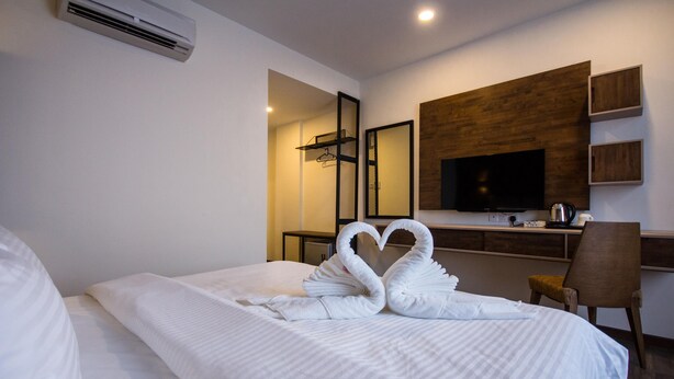 A hotel room with a neatly made bed, a TV, a desk with a coffee maker, and a mirror on the wall. - Wifi Boutique Hotel (George Town)