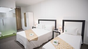 Une chambre d’hôtel avec deux lits, une salle de bain et un miroir encadré de vert.