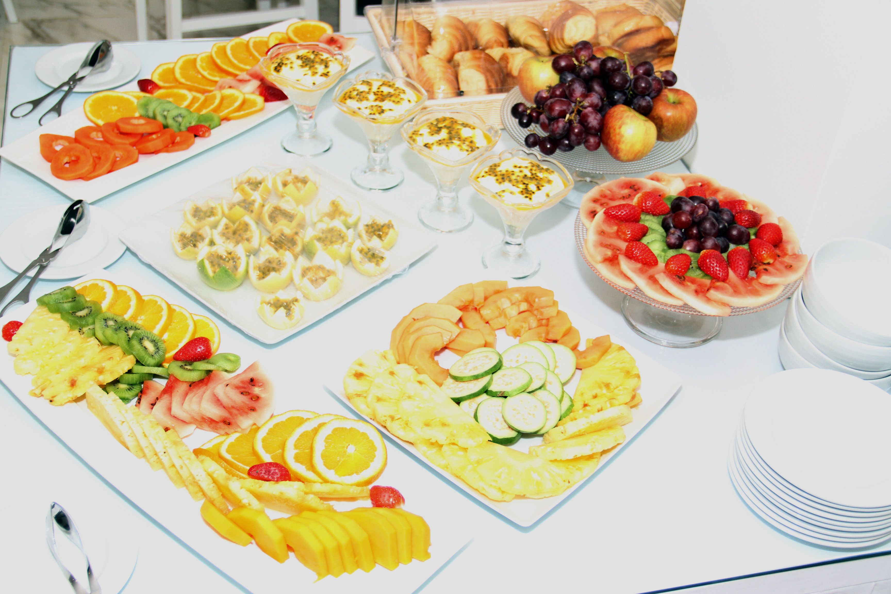 A table with various fruit platters, including sliced oranges, apples, and grapes.