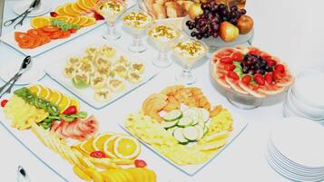 A table with various fruit platters, including sliced oranges, apples, and grapes.