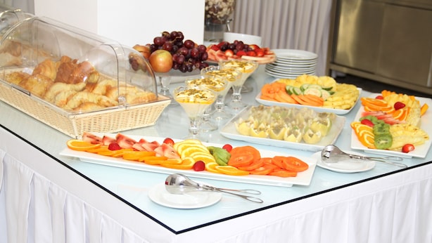 Une table de buffet proposant une variété d’aliments, notamment des fruits, des pâtisseries et des desserts.