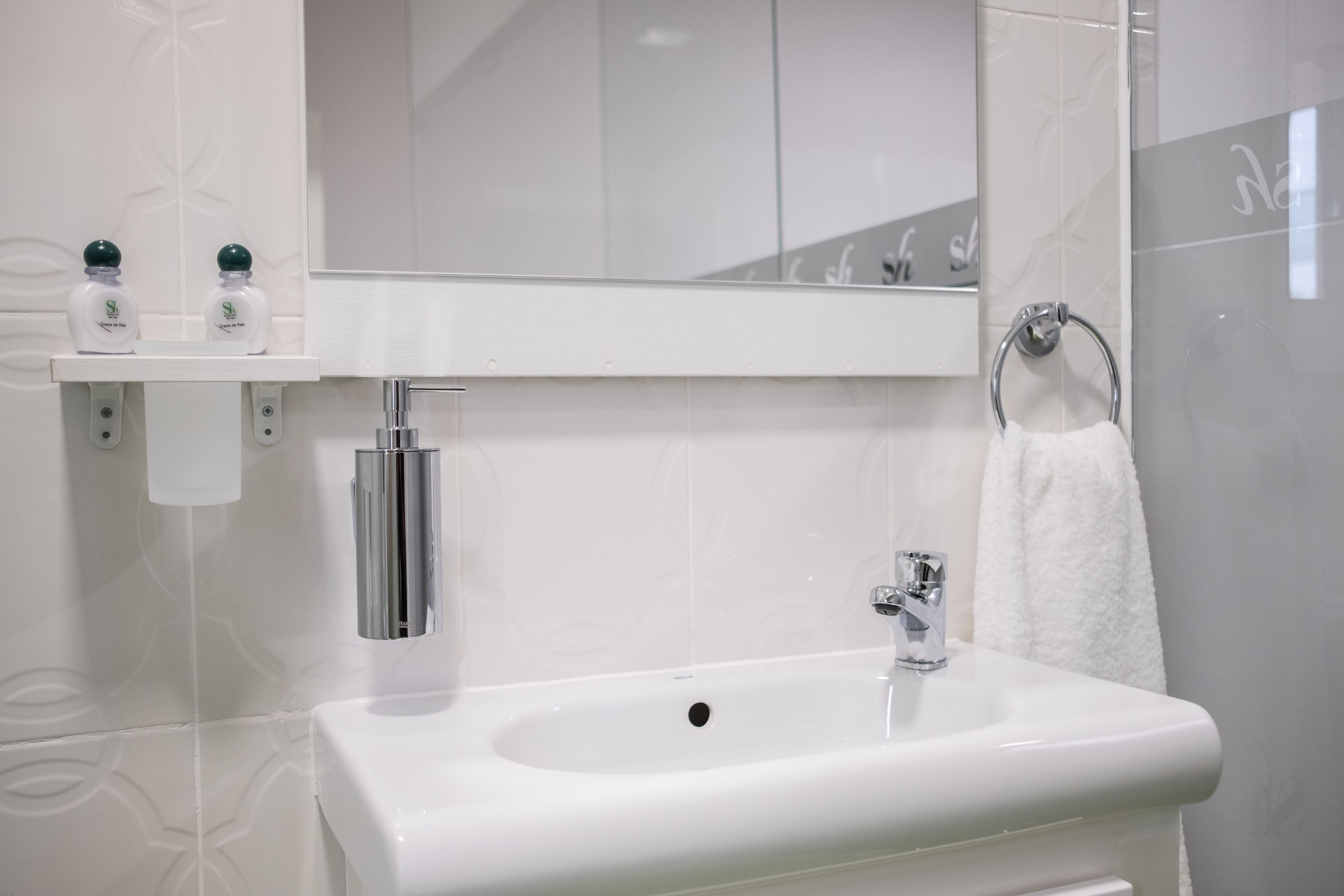 A bathroom with a white sink, a mirror, and a towel rack.
