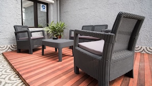 Un espace patio aménagé avec des meubles en osier, une petite table et une plante en pot.
