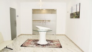 Un espace d’accueil avec une table à plateau en verre, un tapis à motifs et une porte donnant accès à un restaurant.