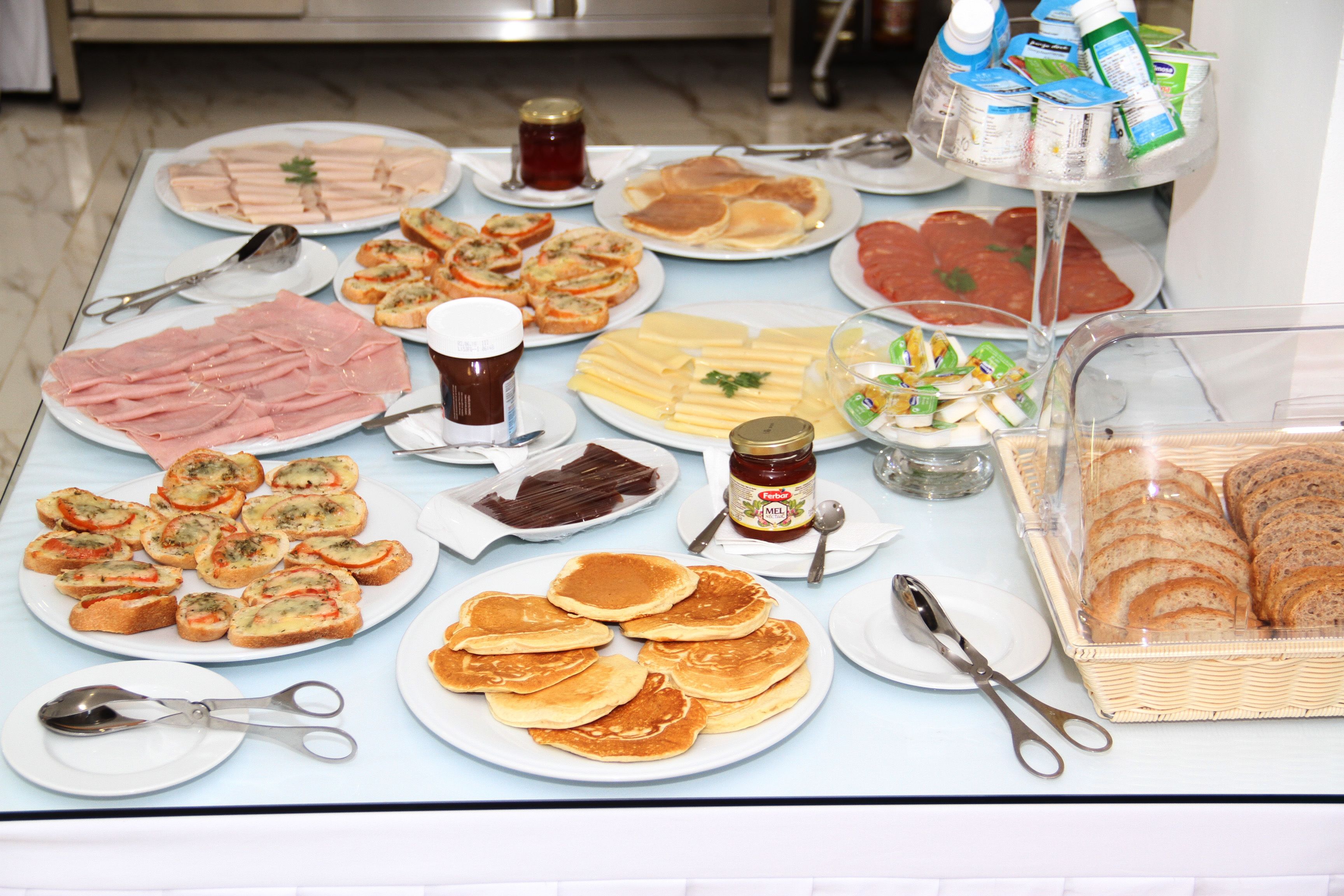 A buffet table with various food items including meats, cheeses, and pastries.