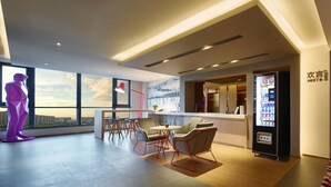 A modern hotel lobby with a reception desk, seating area, vending machine, and large windows offering a city view. - Days Hotel by Wyndham Haikou Meilan Airport (Haikou)