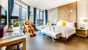 A modern hotel room with a large bed, a desk, a teddy bear, and a city view. - Days Hotel by Wyndham Haikou Meilan Airport (Haikou)