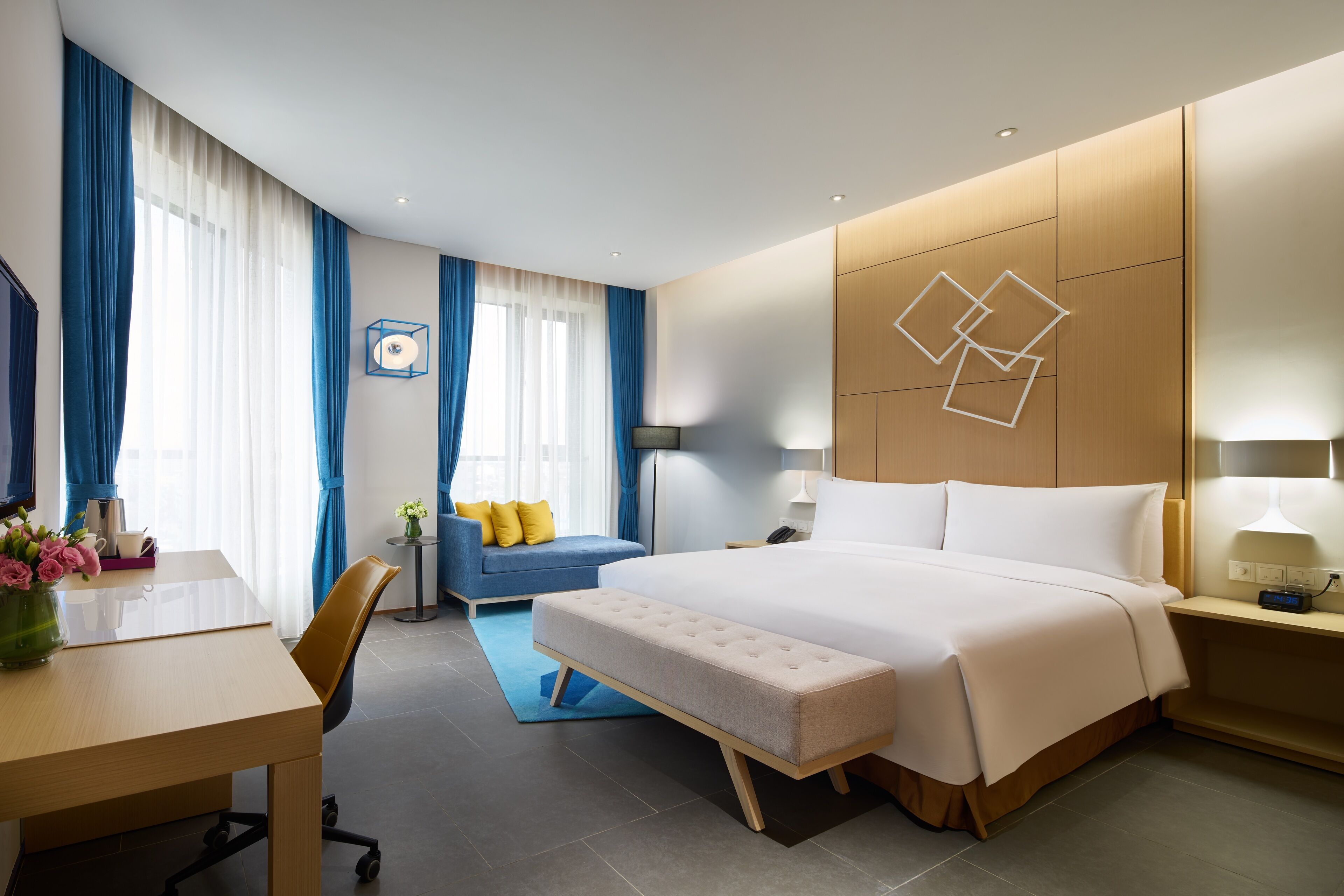 Una habitación de hotel moderna con una cama grande, un escritorio, una silla y un sofá.