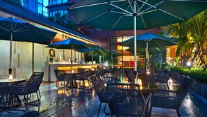 An outdoor seating area with tables and chairs, umbrellas, and a bar. - Days Hotel by Wyndham Haikou Meilan Airport (Haikou)