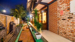 A narrow outdoor corridor with a brick wall on one side and a metal railing on the other. There are potted plants along the corridor. - Villa Kiambang (Seremban)