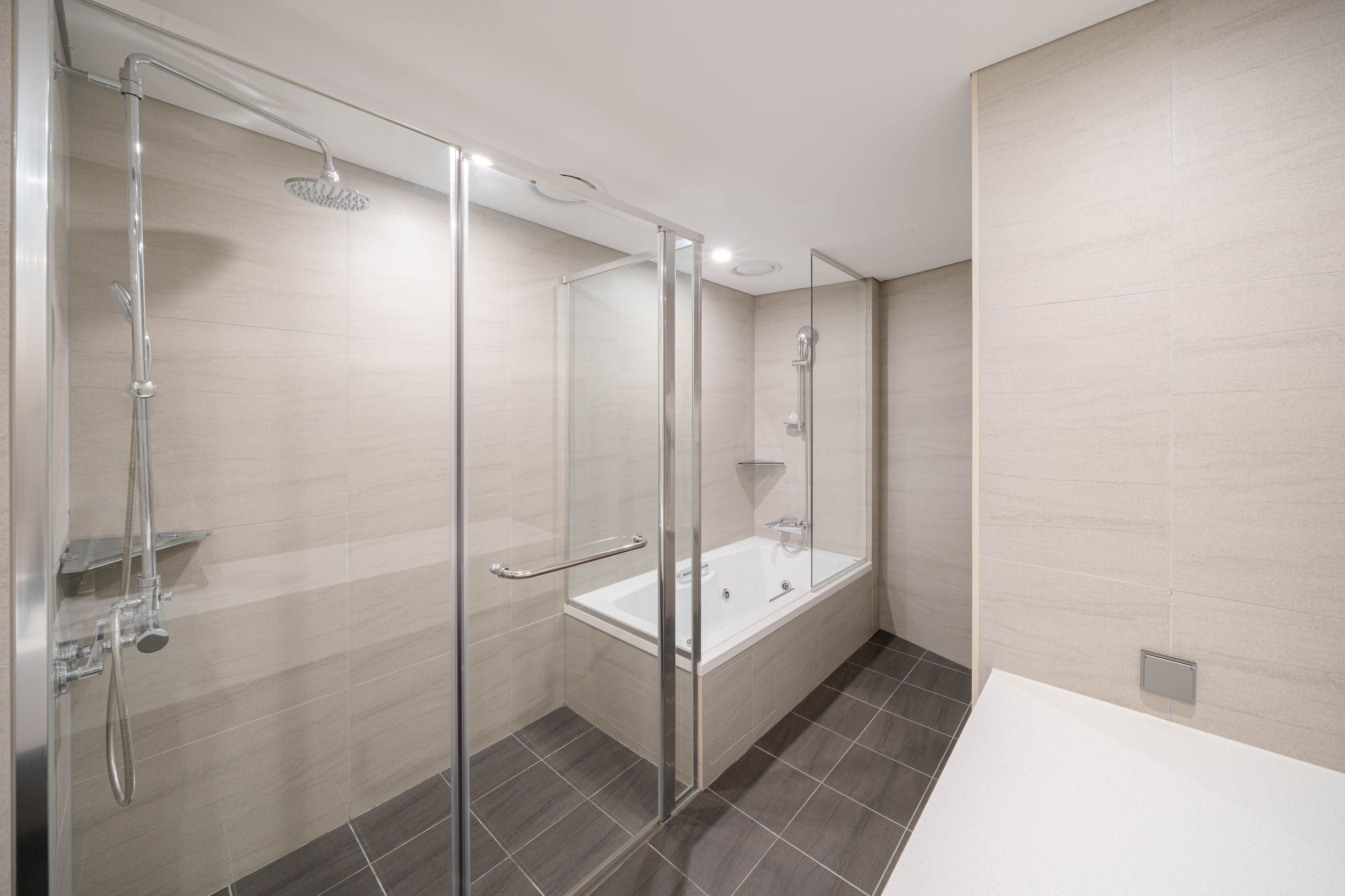 Un baño moderno con ducha de vidrio, bañera independiente y zona de lavamanos separada.