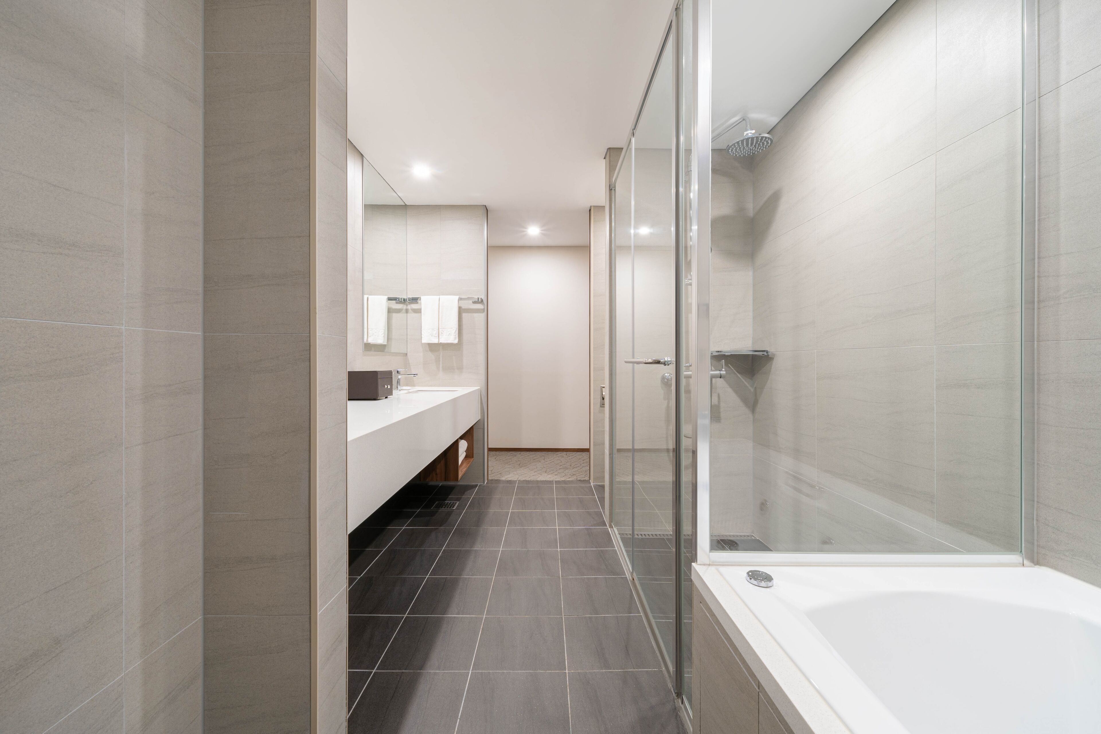 A modern bathroom with a glass shower enclosure, a white bathtub, and a vanity with a mirror.