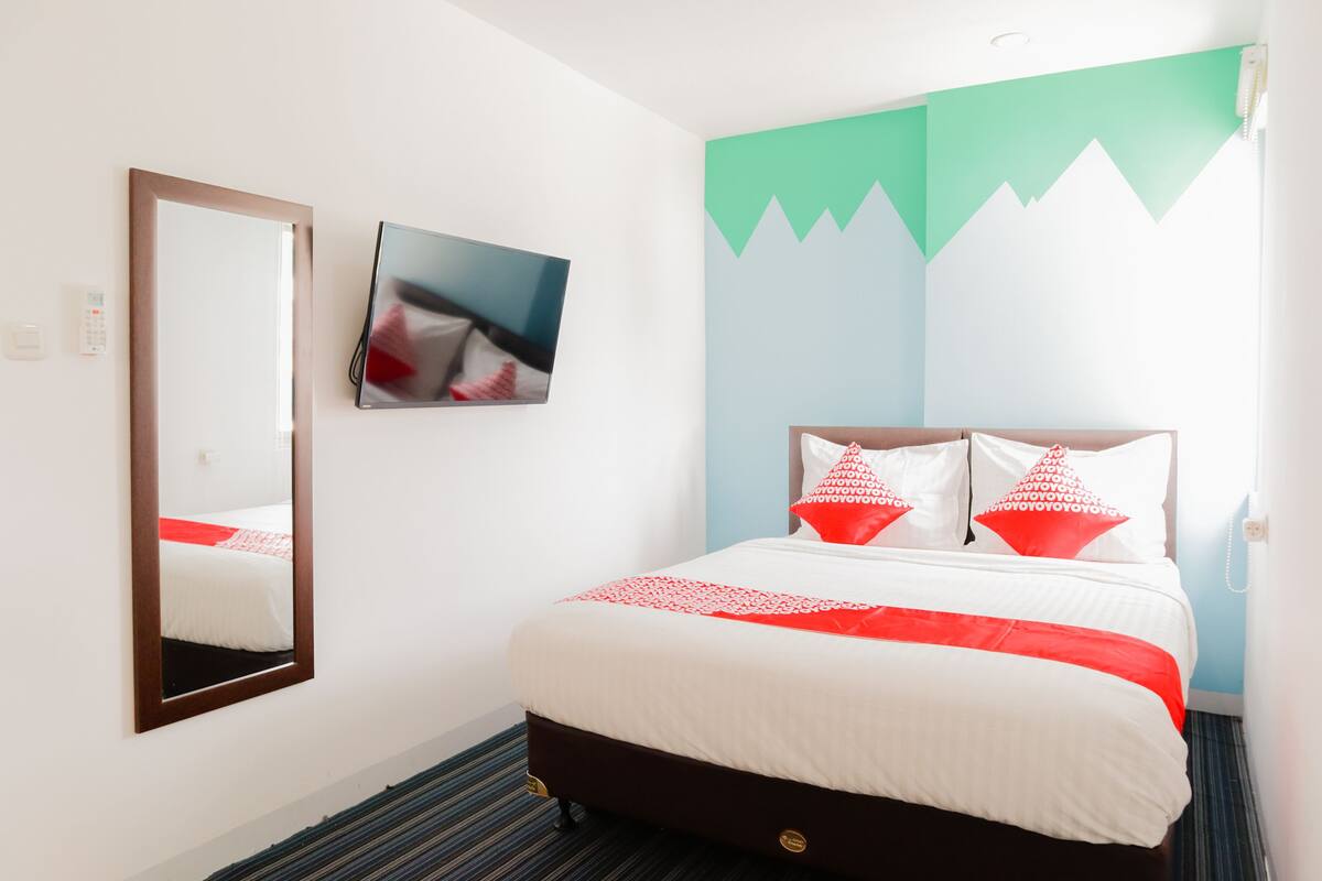 Ein Hotelzimmer mit Bett, Spiegel, Flachbildfernseher und Wandgestaltung mit Bergmotiv.