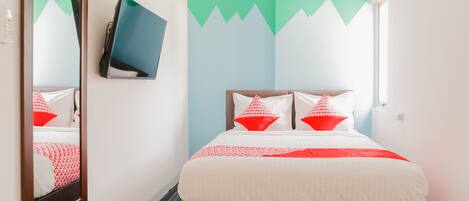 Habitación de hotel con cama, televisor montado en la pared y un mural con motivos de montaña.