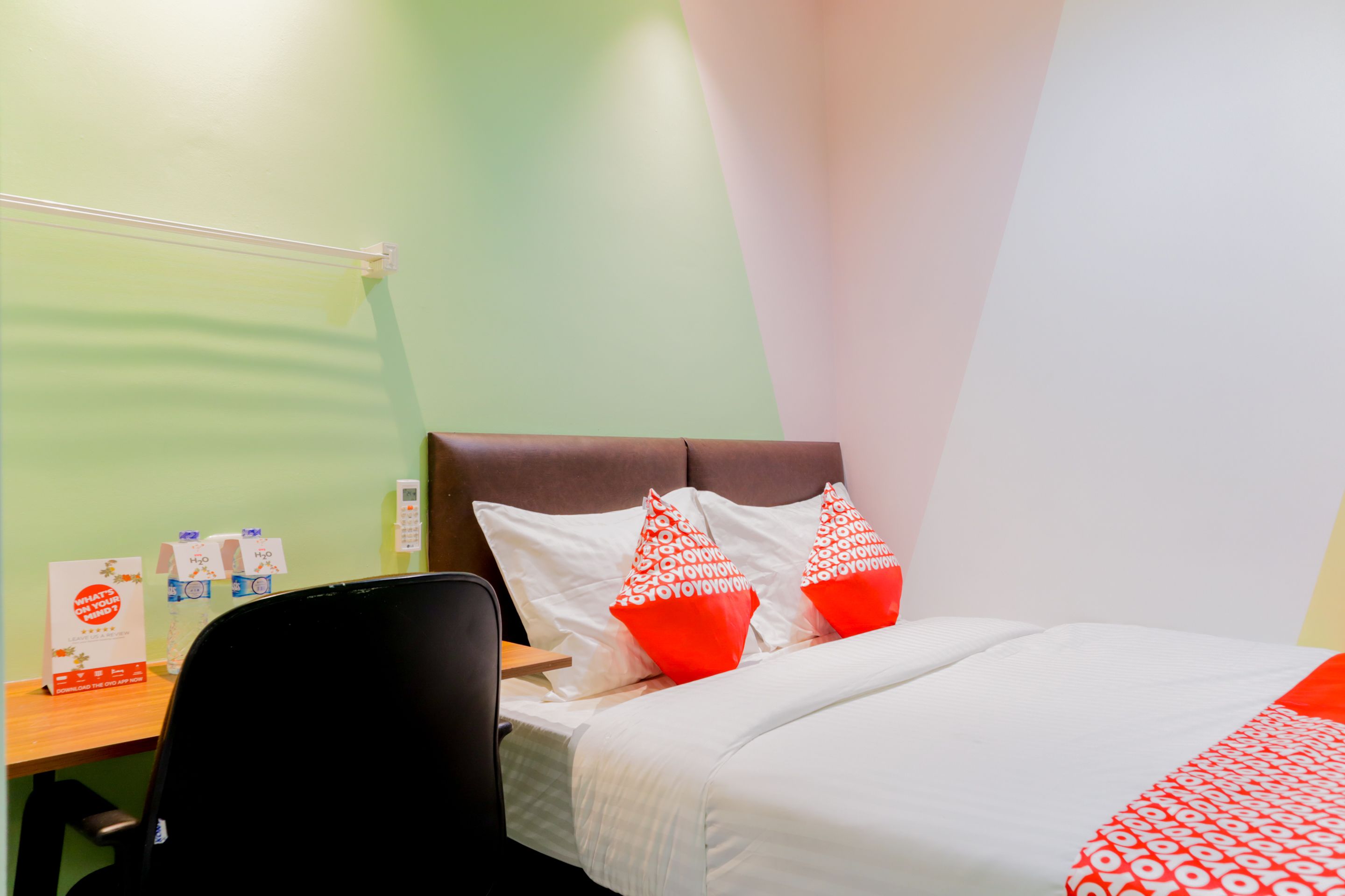 Habitación de hotel con cama, almohadas, escritorio y una silla.