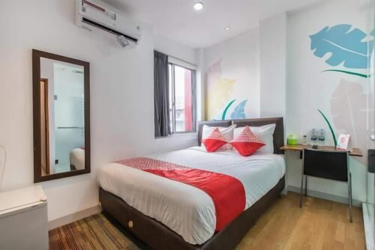 Ein Hotelzimmer mit Bett, Schreibtisch, Spiegel und Fenster.