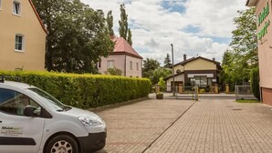 Un camino pavimentado que conduce a la entrada de un hotel, con un acceso vehicular cerrado por una puerta.