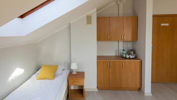 Un dormitorio con cama, mesita de noche, armario de madera y tragaluz.