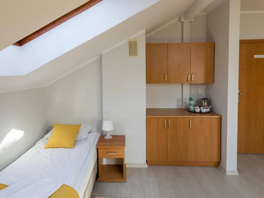 Un dormitorio con cama, mesita de noche, armario de madera y tragaluz.