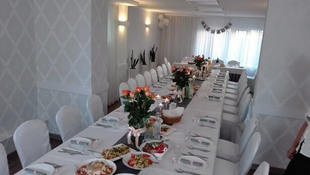 Una larga mesa de comedor con manteles blancos, sillas y centros de mesa florales.