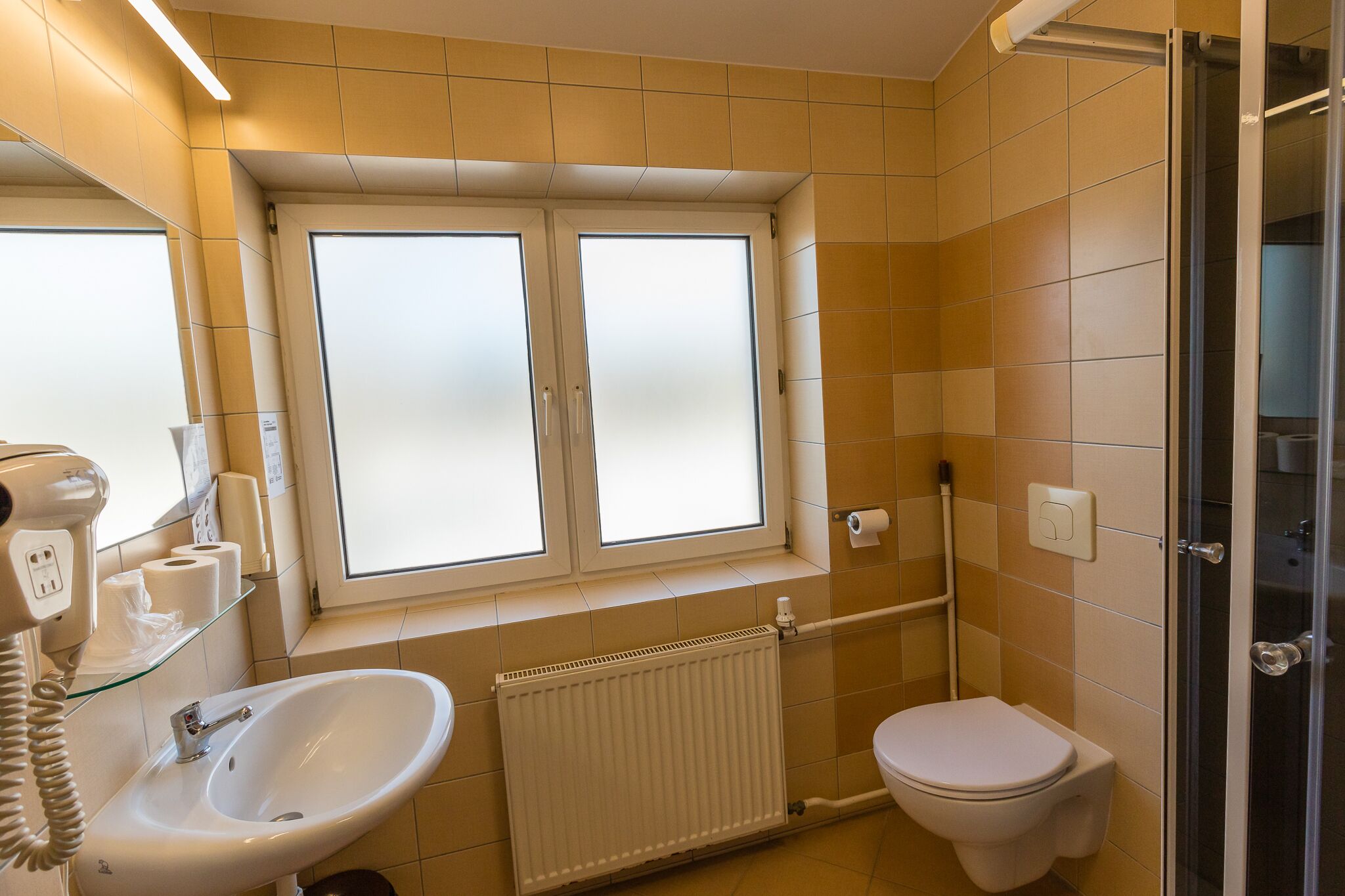 Un baño con lavamanos, inodoro y ventana con vidrio esmerilado.