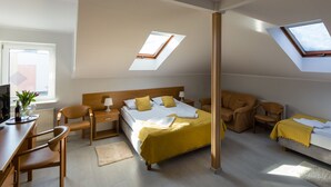 Una habitación de hotel moderna con cama, dos sillas, un escritorio y tragaluces.