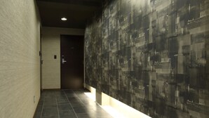 Een gang met een betegelde vloer, een gestructureerde muur en een deur aan het einde.