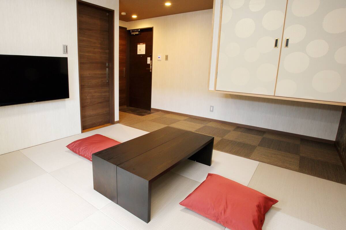 A modern room with a flat-screen TV, a dark wooden table, and a large wardrobe with a polka dot pattern.