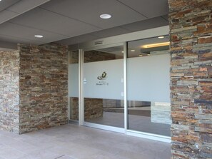 A hotel entrance with stone walls and a glass door. - Hotel Biwako Cerisaie (Otsu)