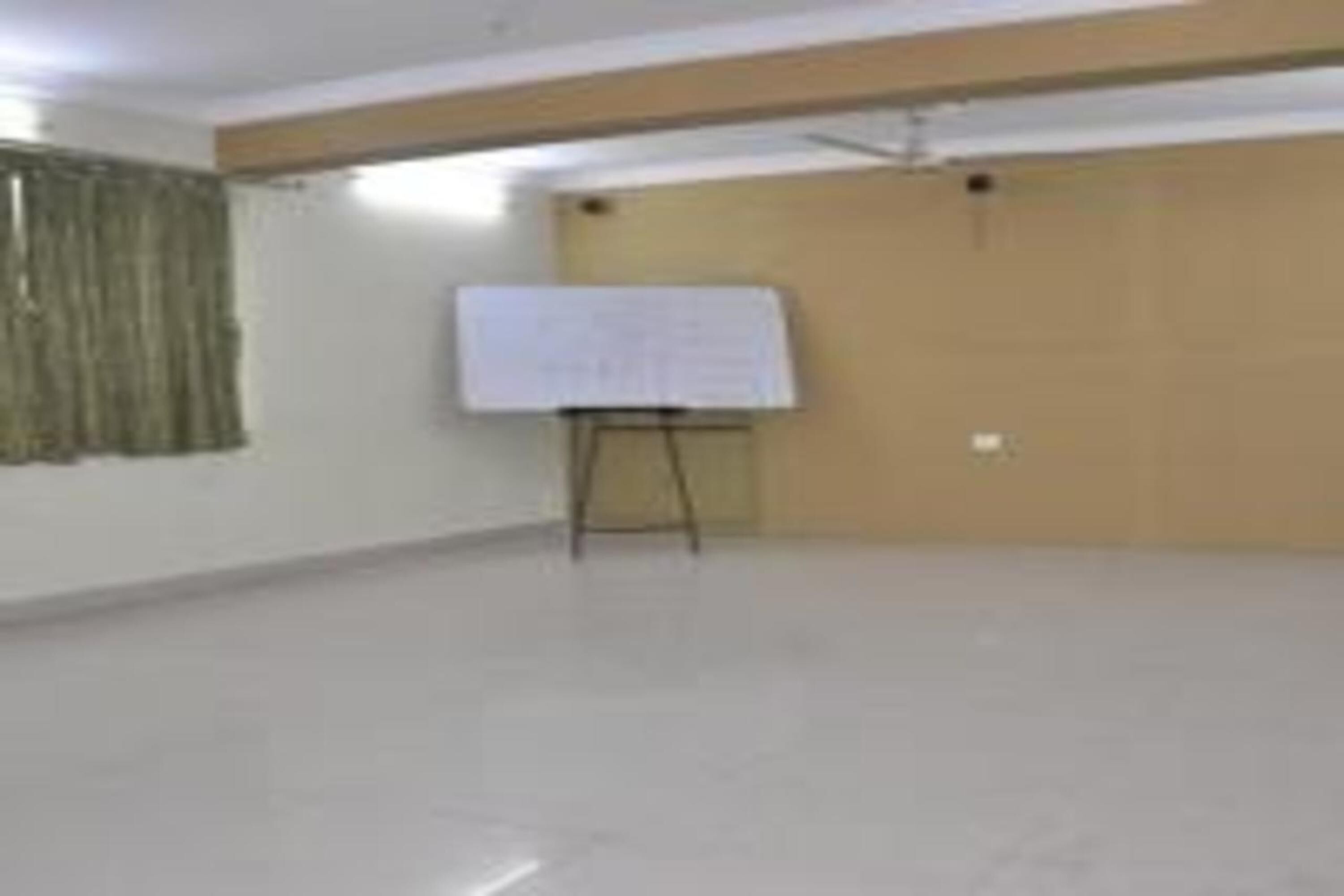 A spacious room with a whiteboard on a stand, a wooden door, and a plain wall.