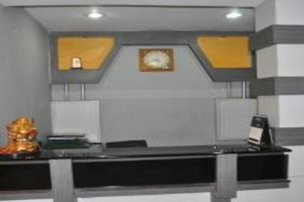 A reception desk with a clock, a small statue, and a sign.