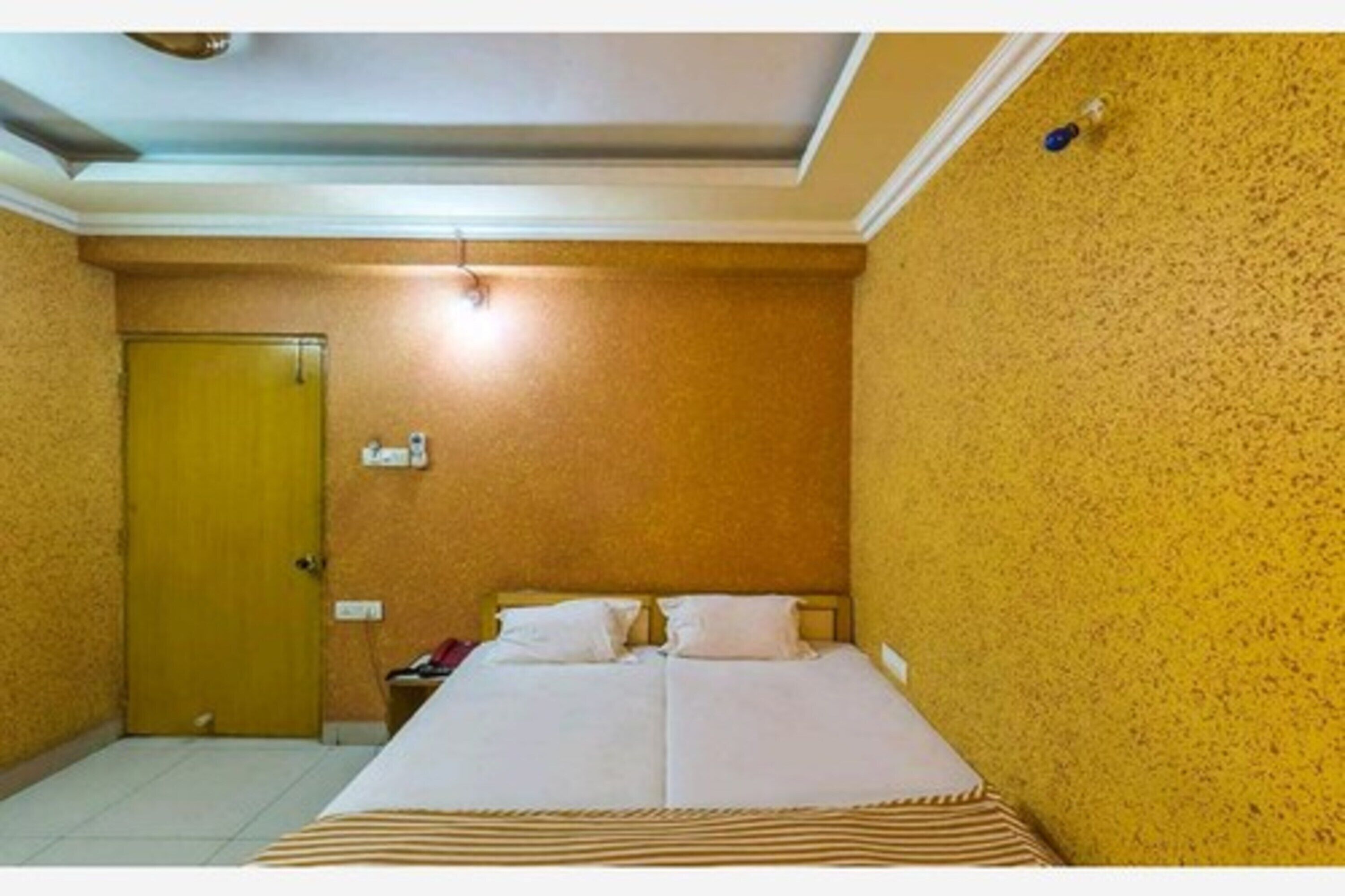 Une pièce avec un lit, une porte et un luminaire au plafond.