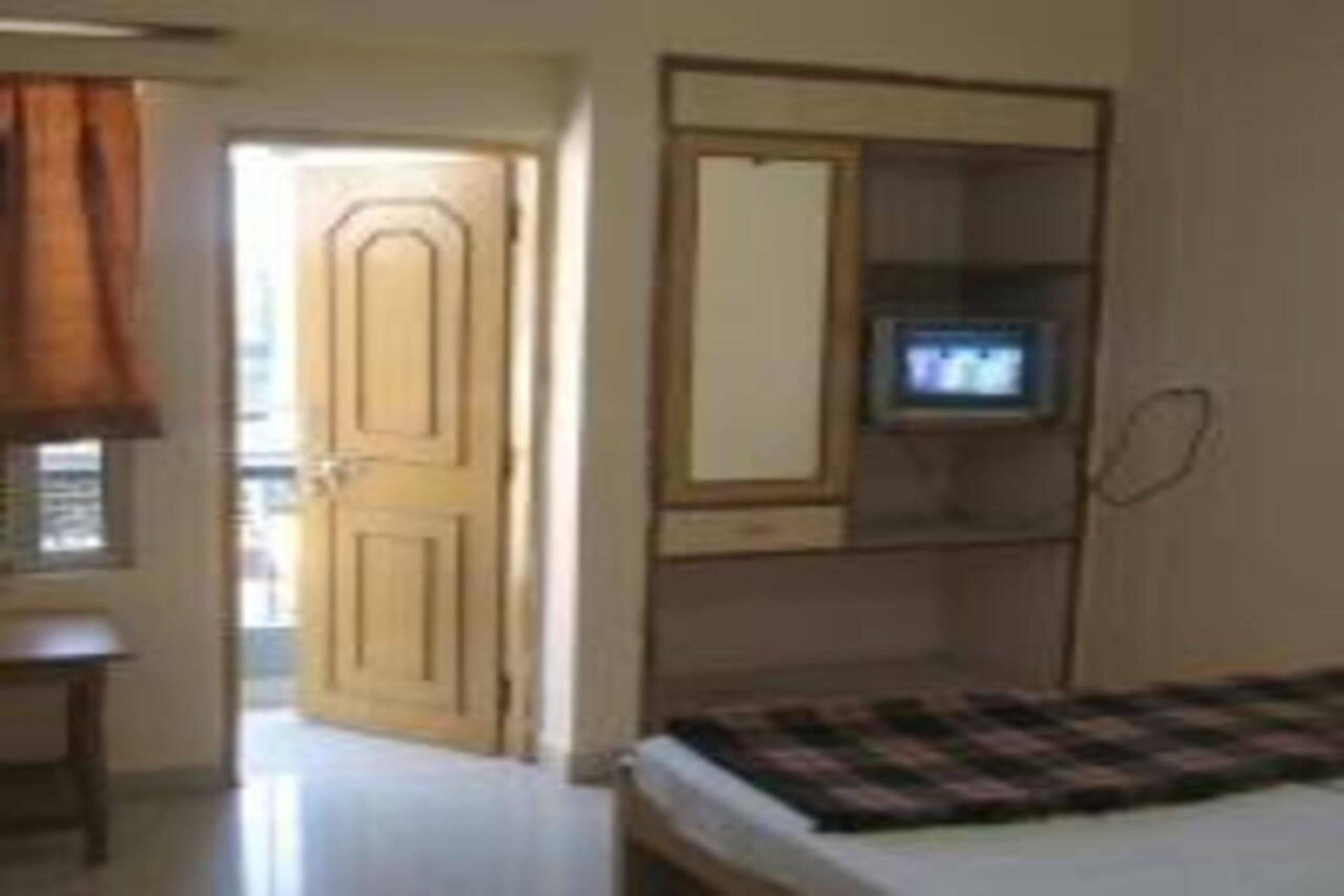 Een slaapkamer met een bed, een televisie op een meubel, een kledingkast en een deur naar een andere kamer.