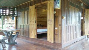 Eine Holzhütte mit Bett, Tisch und Fenster.