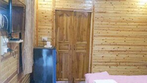 Ein Zimmer mit Holzwänden, einem Bett, einem kleinen Schreibtisch und einem Kleiderschrank.