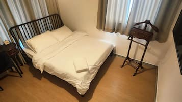 A hotel room with a bed, a bedside table, a chair, a TV, and curtains.