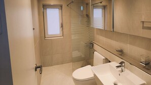 Un baño moderno con inodoro, lavamanos y ducha.