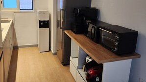 Una cocina compacta con nevera, microondas y cafetera sobre una encimera de madera.